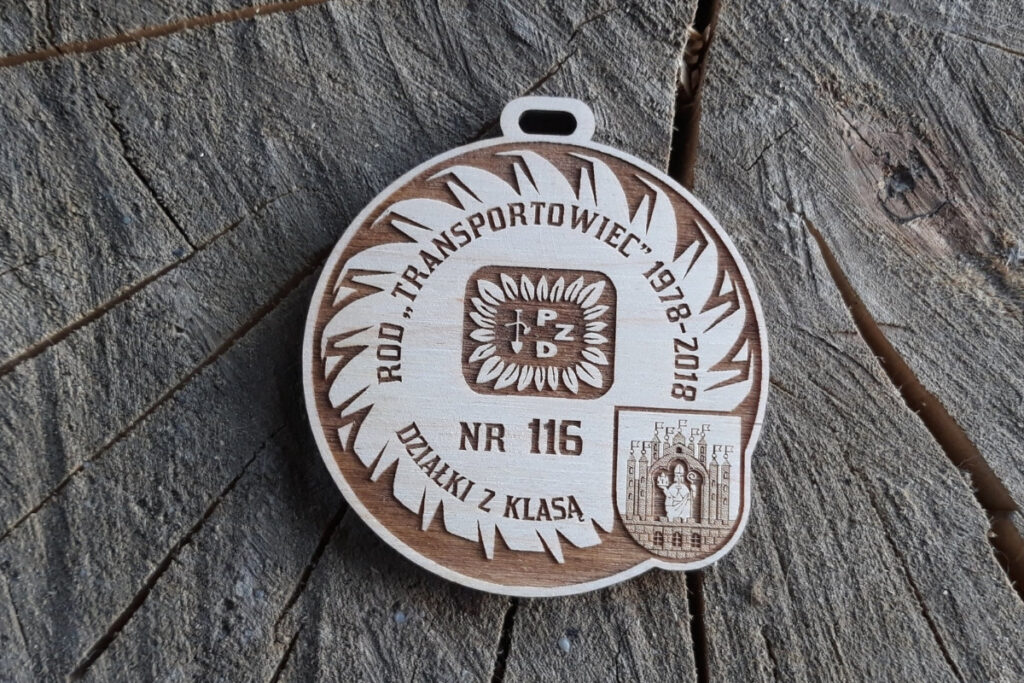 Okrągły drewniany medal jubileuszowy RPD Transportowiec 1978-2018 z grawerem logotypu i napisem "Działki z klasą" i logiem.