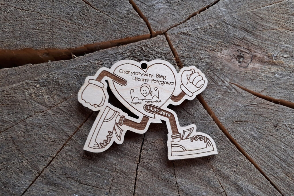 Medal z drewna w formie "biegnącego serca" z grawerem logotypu Potęgowa i napisem pamiątkowym.