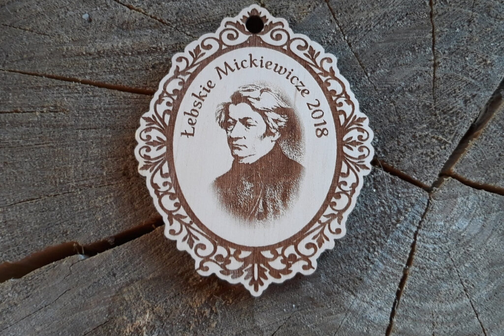 Ozdobny drewniany medal „Łebskie Mickiewicze 2018” z grawerowanym popiersiem Adama Mickiewicza.
