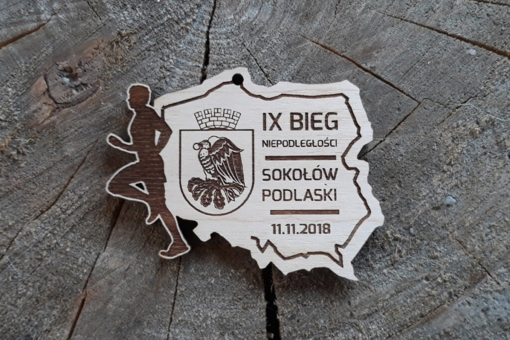 Medal wycinany laserowo w konturu Polski z grawerem biegacza i godłem, pamiątka z Sokołowa Podlaskiego.