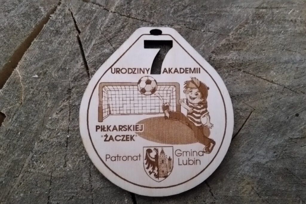 Drewniany medal dla dzieci na 7. urodziny Akademii Piłkarskiej z grawerem piłki wpadającej do bramki.