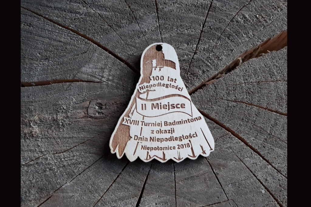Drewniany medal w kształcie lotki do badmintona na XVIII Turniej z okazji Dnia Niepodległości.