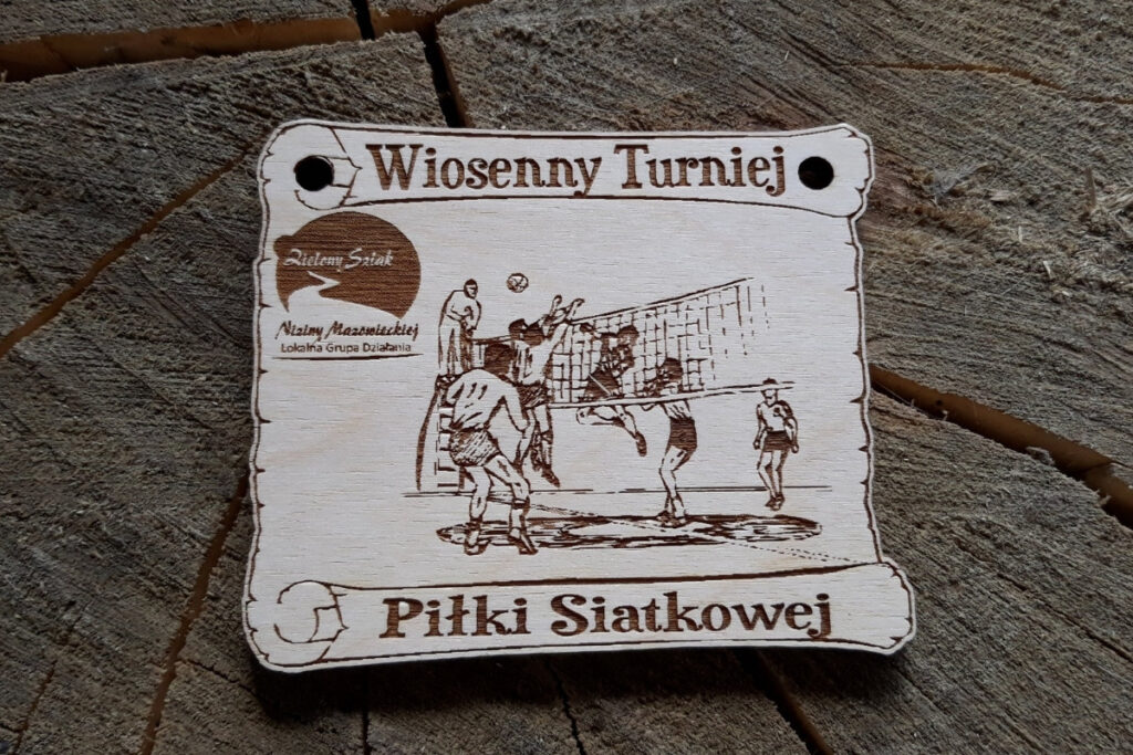 Drewniany medal na Wiosenny Turniej Piłki Siatkowej z grawerem piłki do siatkówki przelatującej nad siatką oraz graczami po obu stronach siatki.