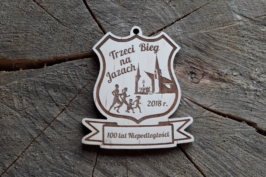Medal wykonany z jasnego drewna z grawerem laserowym. W górnej części znajduje się napis 'III Bieg na Jazach'.