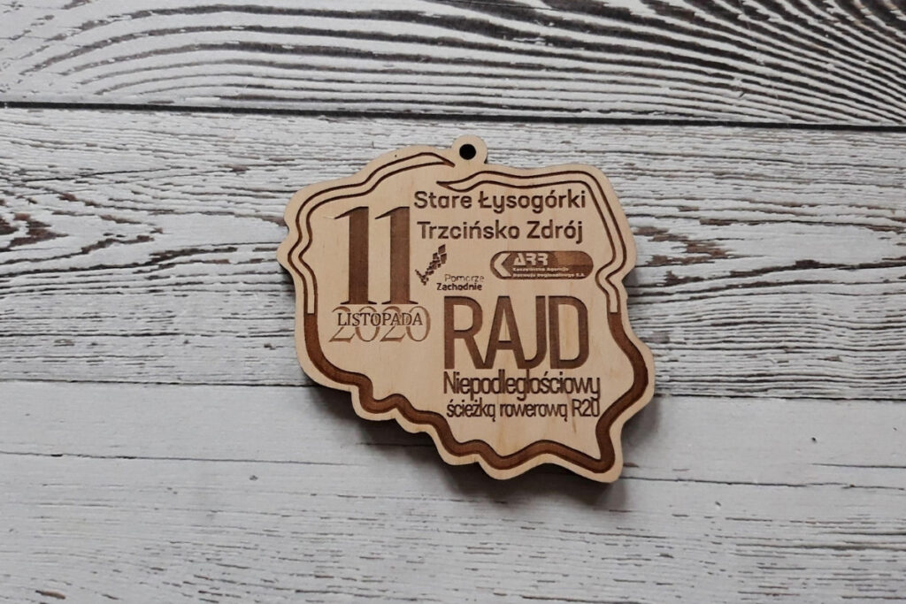 Wyjątkowy drewniany medal w kształcie konturów Polski z grawerem pamiątkowym  - nazwą wydarzenia oraz logotypami.