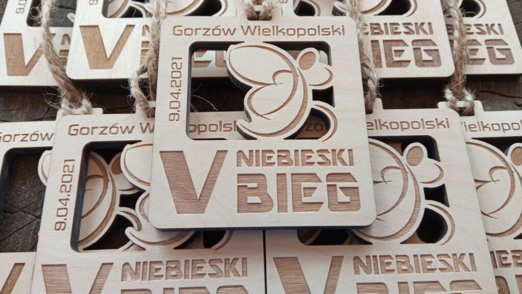 Drewniany medal ażurowy przygotowany na „Niebieski Bieg”, z precyzyjnym grawerem logotypu wydarzenia, datą oraz symbolicznymi wycięciami podkreślającymi lekkość formy.