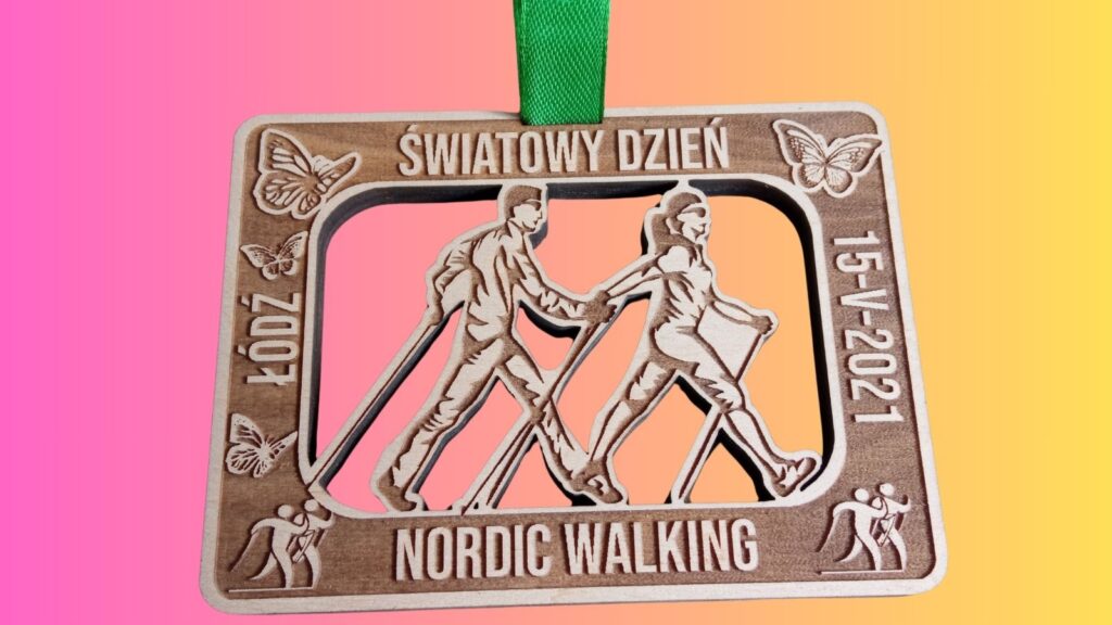 Prostokątny drewniany medal na Światowy Dzień Nordic Walking, z ażurowo wyciętymi postaciami osób maszerujących z kijami wewnątrz tarczy medalu.