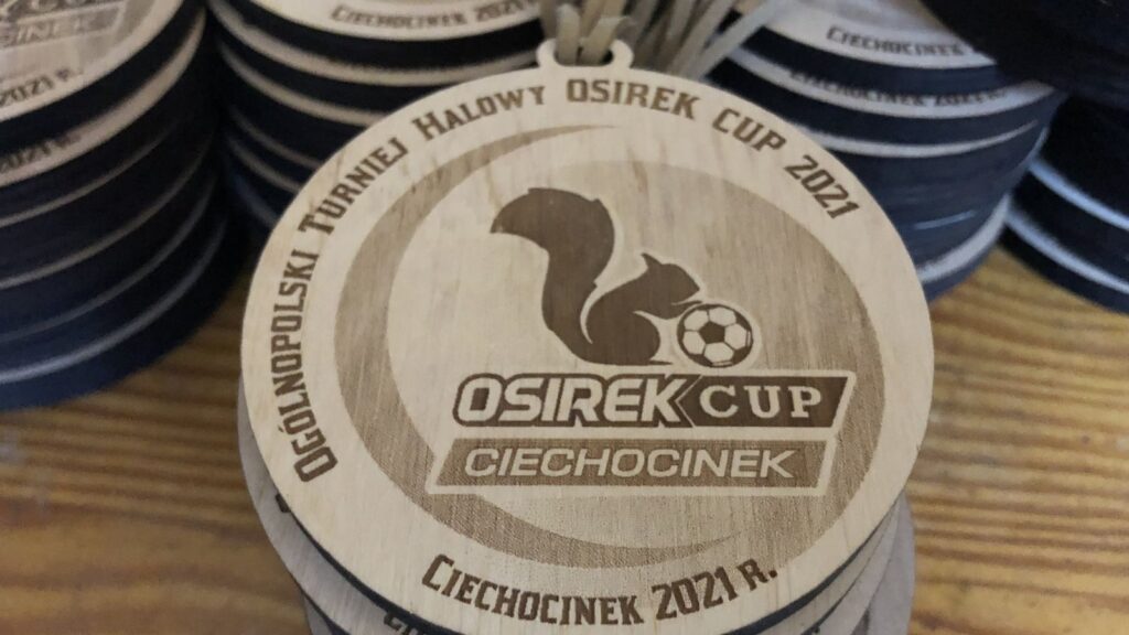 Okrągły drewniany medal na Ogólnopolski Turniej Halowy Piłki Nożnej z centralnie umieszczonym logotypem organizatora.