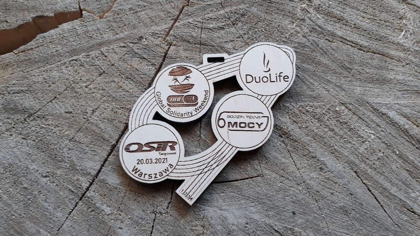 4 logotypy i bieżnia lekkoatletyczna. Drewniany medal ażurowy