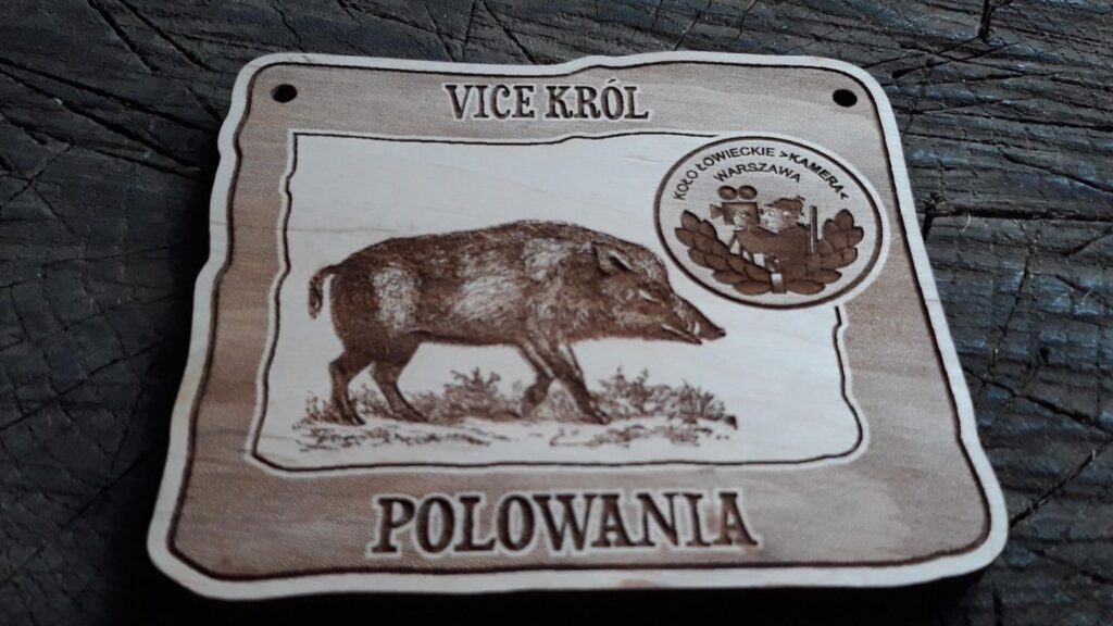 Prostokątny drewniany medal dla Vice Króla Polowania z grawerem biegnącego dzika, oraz logotypem koła łowieckiego, wykonany z jasnej brzozy bez śladów osmaleń.