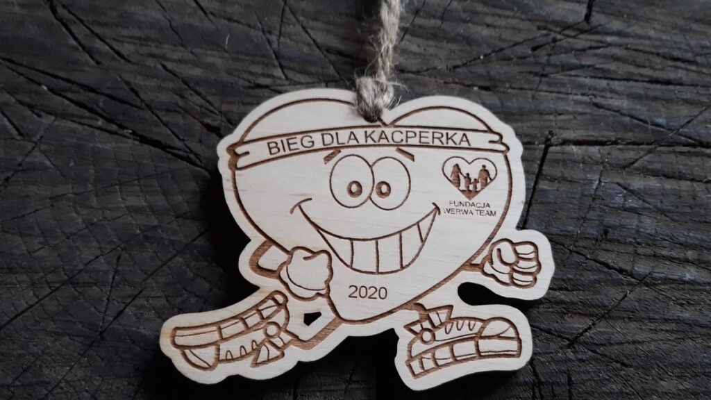 Drewniany medal na bieg charytatywny z grawerem „Biegnącego Serca” w butach sportowych, napisem „Bieg dla Kacperka” oraz miejscem na logo fundacji, wykonany z czystej brzozy bez śladów dymu.sklejki brzozowej.