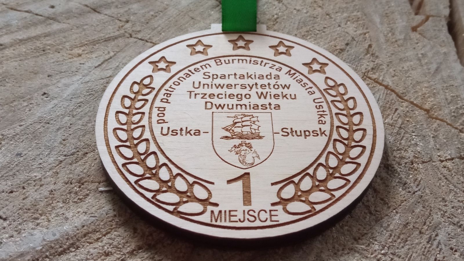 Spartakiada Uniwersytetu Trzeciego Wieku. Okrągłe drewniane medale grawerem zajętego miejsca.