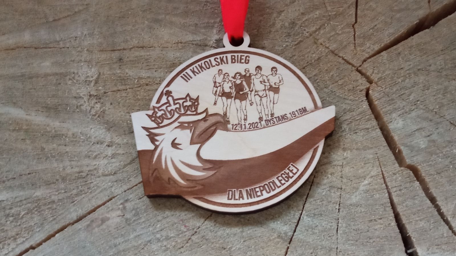 III Kikolski Bieg dla Niepodległej – drewniany medal z biegaczami, Orłem w koronie i Flagą Polski. Medal patriotyczny.