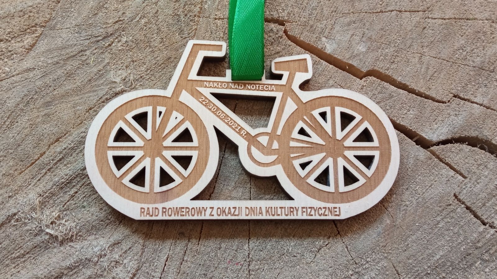 Drewniany medal w kształcie roweru z ażurowymi wycięciami.
