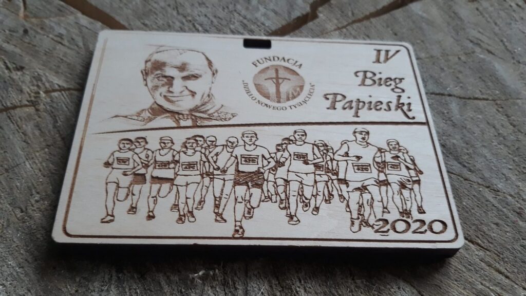 IV Bieg Papieski – drewniany medal z biegaczami, popiersiem Jana Pawła II, logiem Fundacji