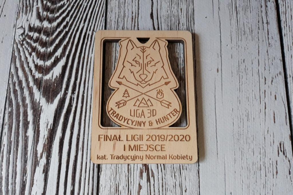 Prostokątny drewniany medal łuczniczy z precyzyjnym, ażurowym wycięciem logotypu Ligi 3D oraz napisami na dole