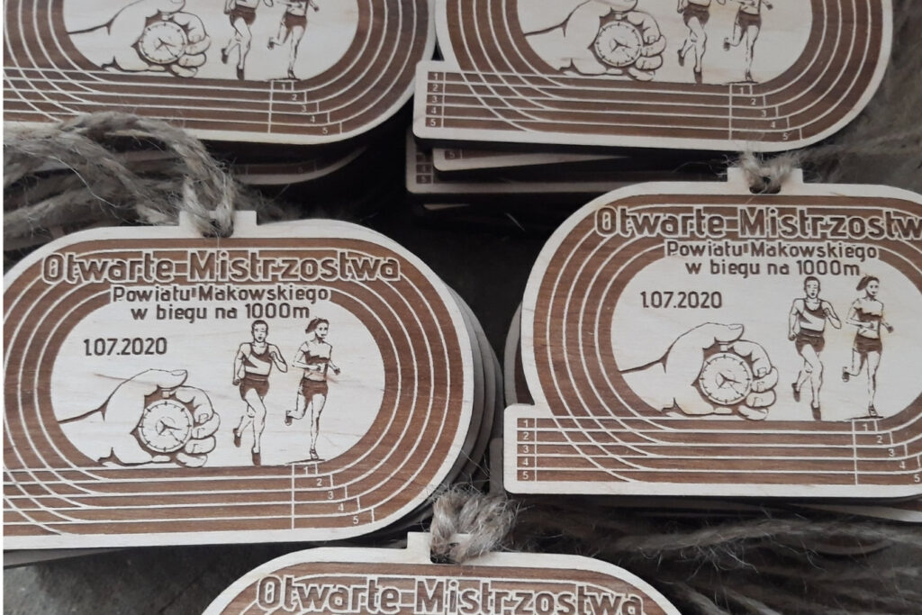 Oryginalny drewniany medal na mistrzostwa lekkoatletyczne, wycięty w charakterystycznym kształcie owalnej bieżni stadionowej z grawerem torów.