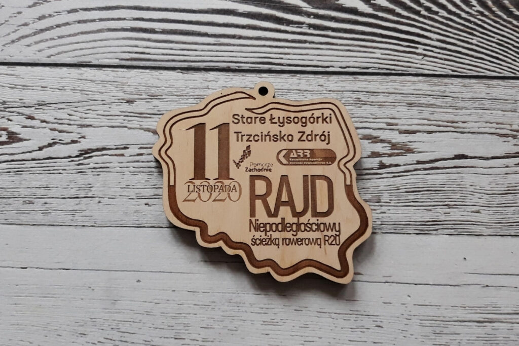 Drewniany medal o nieregularnym kształcie konturów Polski, przygotowany na Rajd Niepodległościowy.
