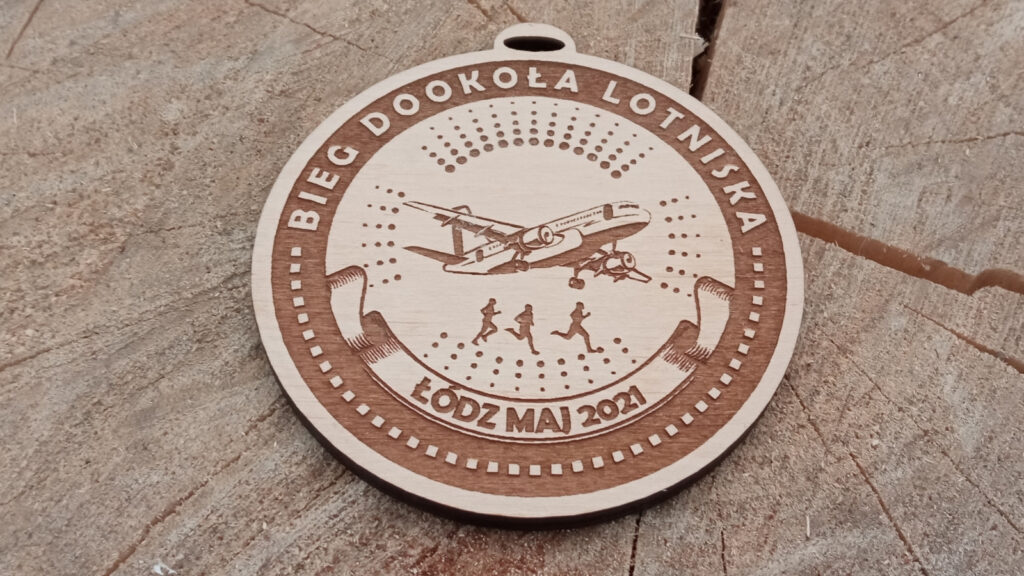 Okrągły drewniany medal na „Bieg dookoła Lotniska” z precyzyjnym grawerem przedstawiającym startujący samolot pasażerski, w eleganckiej okrągłej ramce.