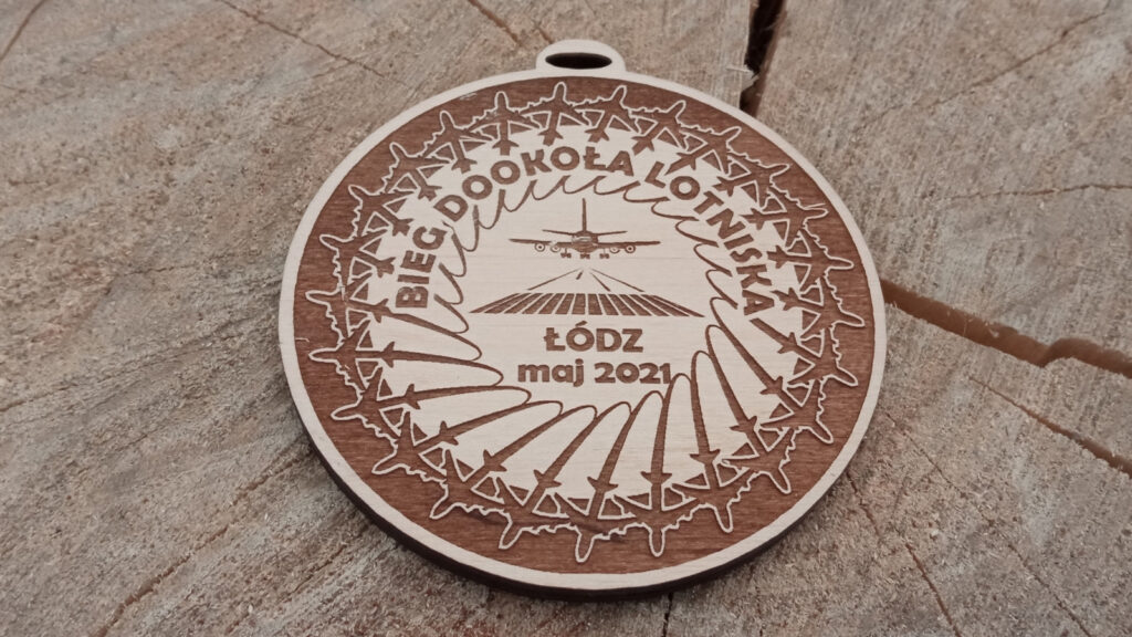 Okrągły drewniany medal na „Bieg dookoła Lotniska” z precyzyjnym grawerem przedstawiającym startujący samolot pasażerski, w eleganckiej okrągłej ramce z motywem lotniczym.