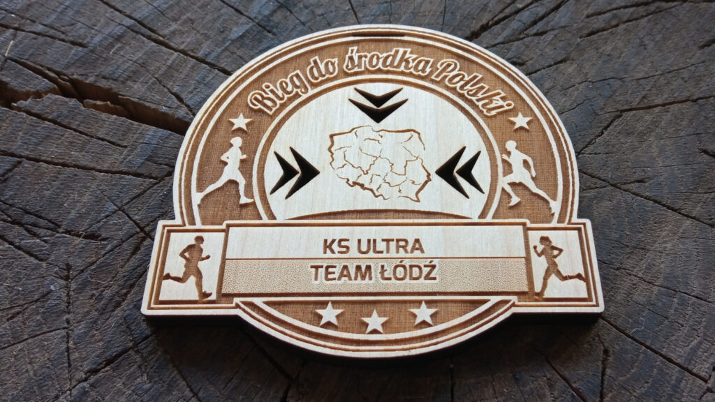 Drewniany medal o solidnej grubości 6 mm na „Bieg do Środka Polski”, z grawerowanym konturem mapy Polski, precyzyjnie zaznaczonym geometrycznym środkiem kraju oraz sylwetkami dynamicznie biegnących zawodników.
