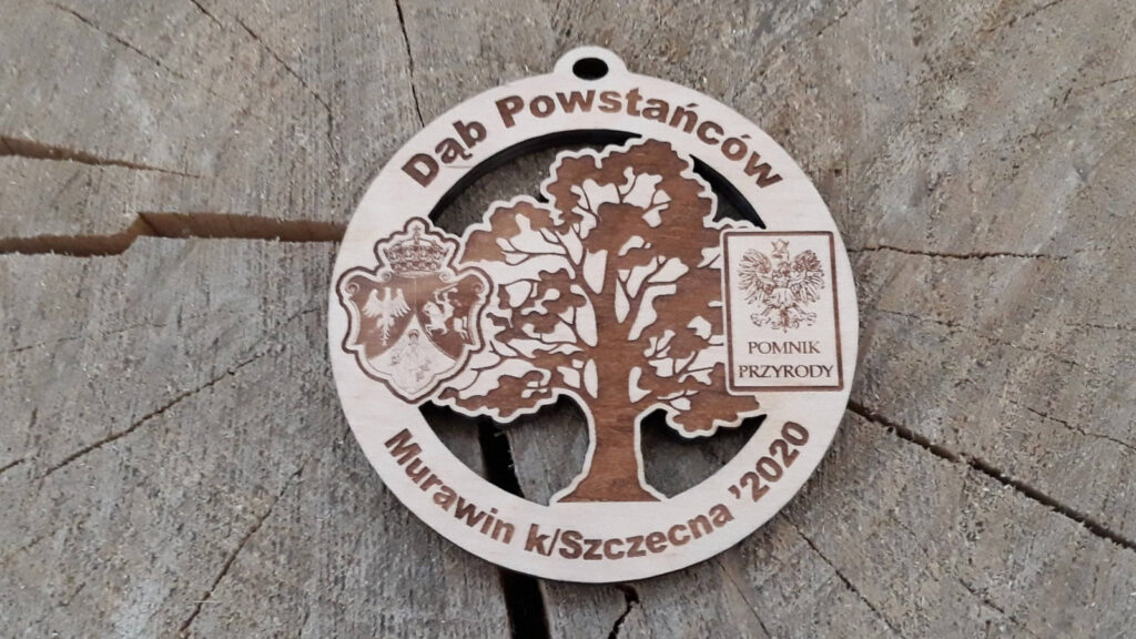 Dąb Powstańców – drewniany okrągły medal z ażurowo wyciętym dębem oraz logotypami