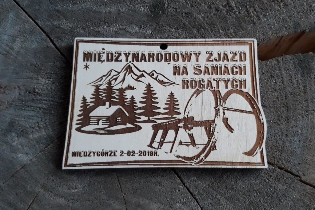 Drewniany medal pamiątkowy z grawerem sań rogatych na Międzynarodowy Zjazd w Międzygórzu.