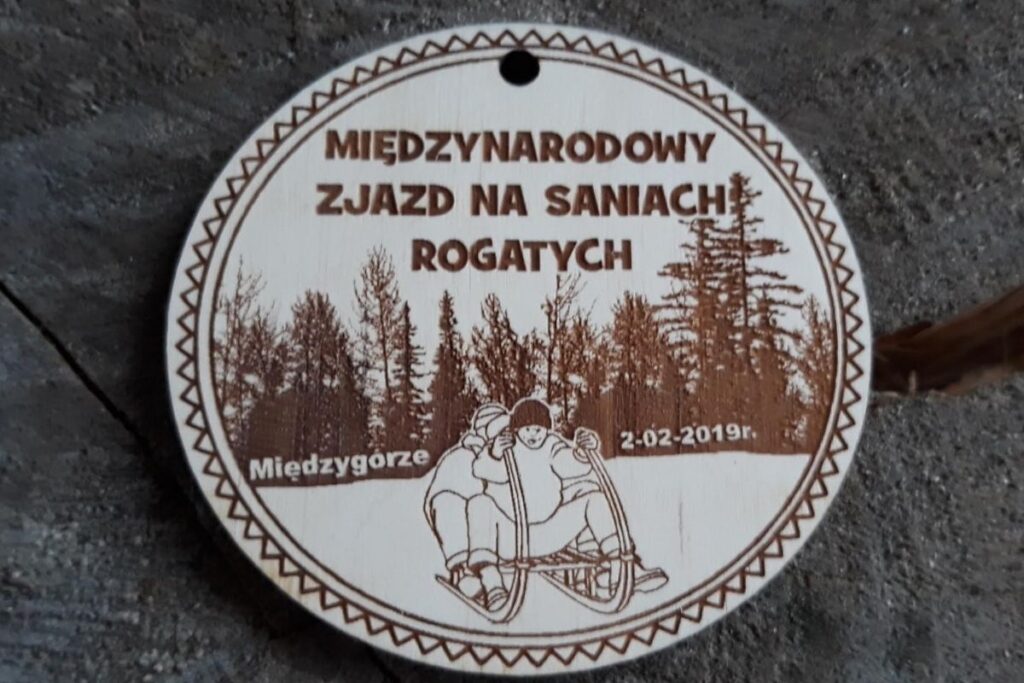 Drewniany medal pamiątkowy z grawerem sań rogatych na Międzynarodowy Zjazd w Międzygórzu.
