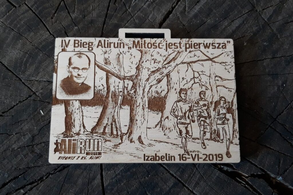 Drewniany prostokątny medal z wizerunkiem ks. Aleksandra Federowicza i cytatem „Miłość Jest Pierwsza” Drewniany prostokątny medal z wizerunkiem ks. Aleksandra Federowicza i cytatem „Miłość Jest Pierwsza”