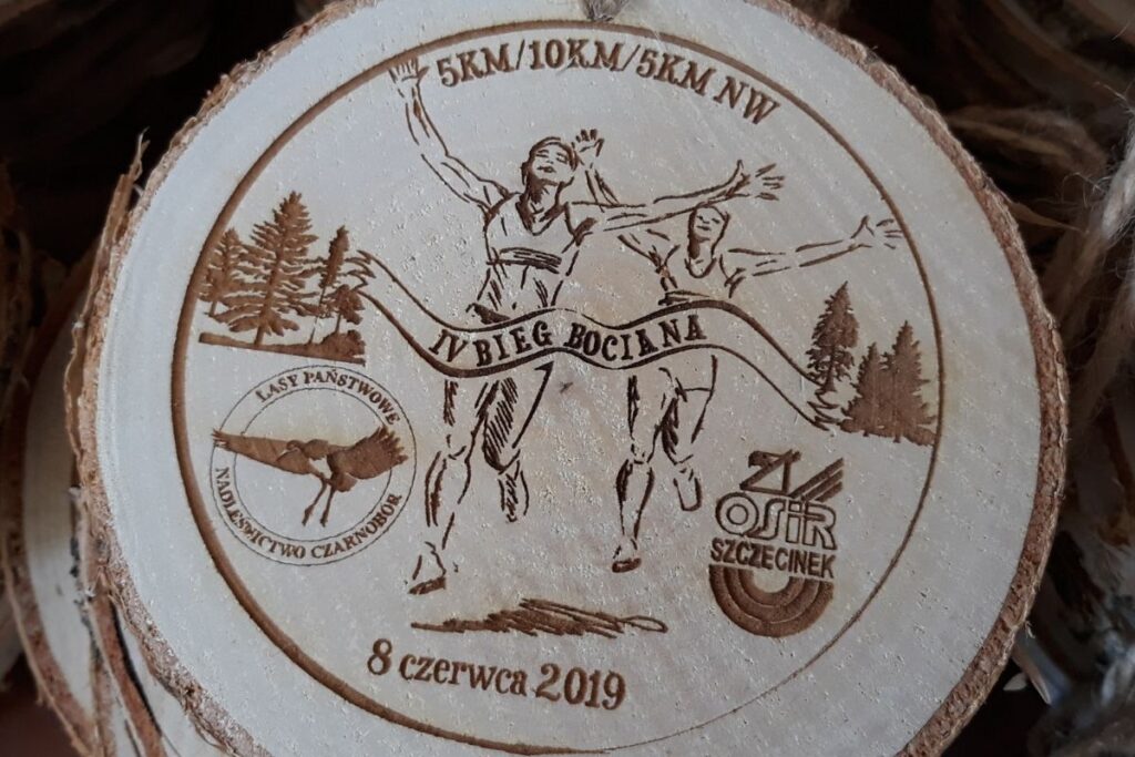 Medal z plastra drewna z korą, ekologiczne trofeum Bieg Bociana, pamiątka z biegu na plastrze brzozy, grawerowany medal naturalistyczny.