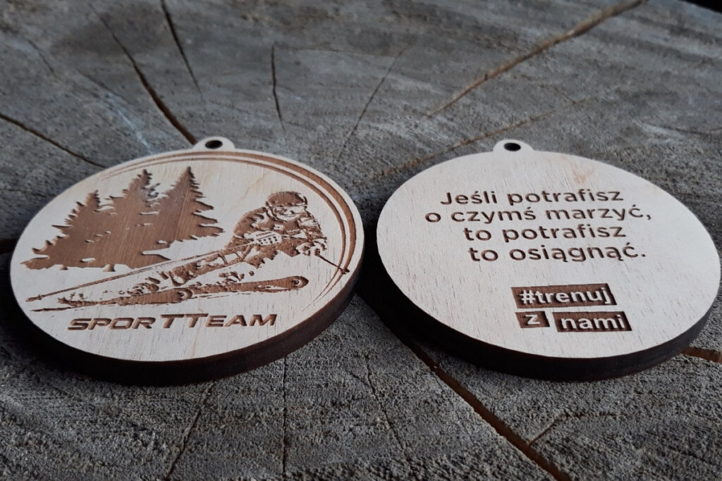 Drewniany medal z narciarzem i motywującym cytatem
