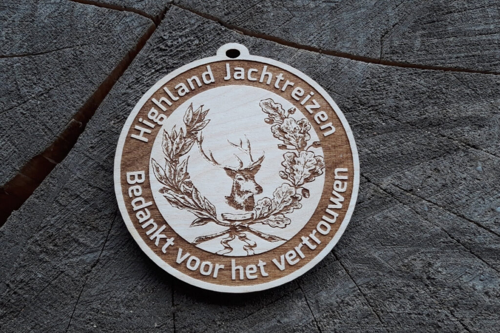 Okrągły drewniany medal z precyzyjnym grawerem głowy koziołka (sarny) w otoczeniu klasycznego wieńca dębowego.
