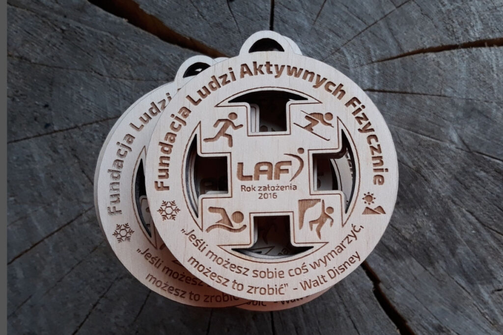 Okrągły drewniany medal z ażurowymi wycięciami, logiem  cytatem.