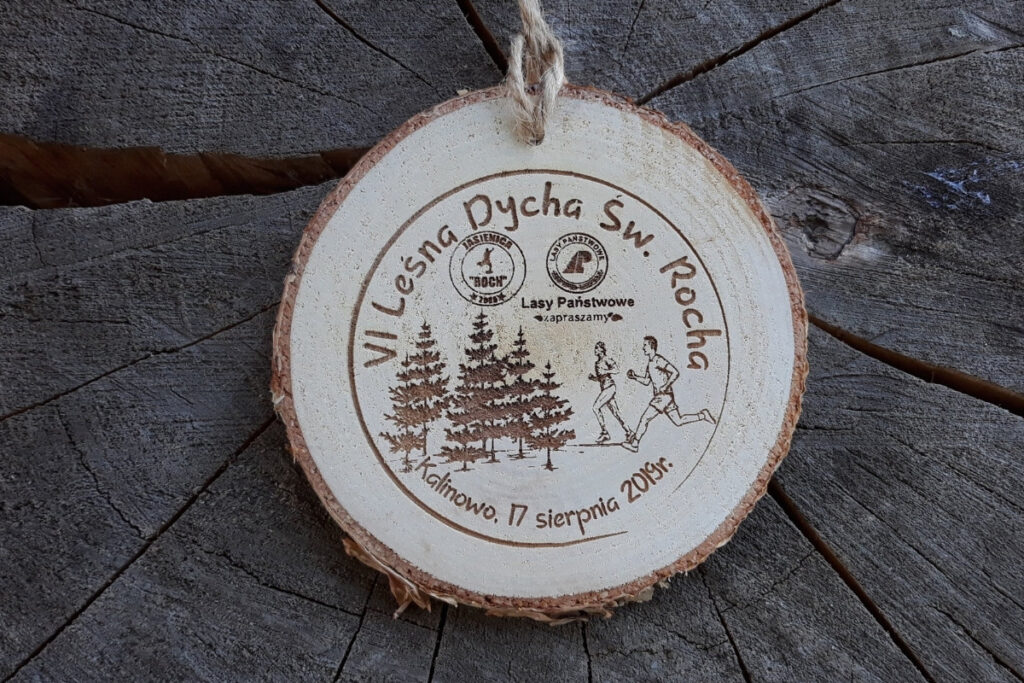 Medal z naturalnego plastra brzozy z korą, z grawerem logotypu Leśna Dycha, sylwetką biegacza na szlaku i rokiem edycji.