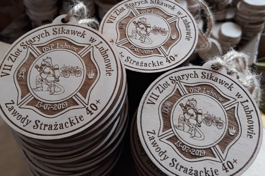 Okrągły drewniany medal z grawerem zabytkowej sikawki konnej, herbem OSP oraz napisem VII Zlot Starych Sikawek Strażackich w Lubnowie.”