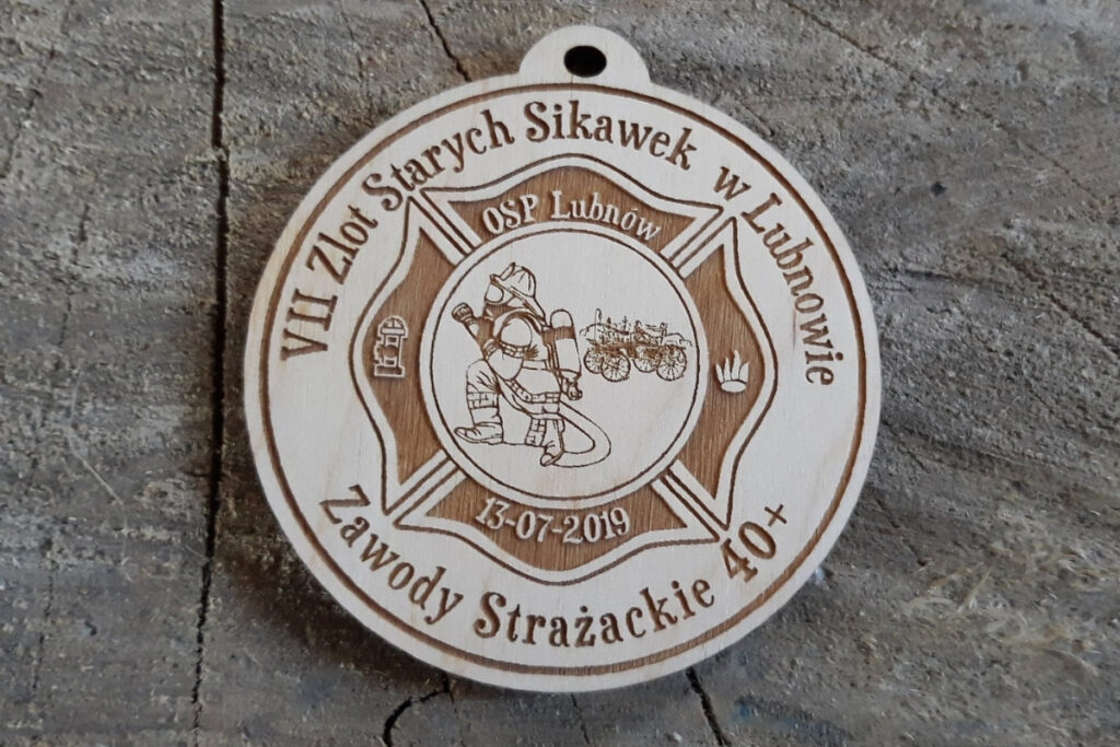 Okrągły drewniany medal z grawerem zabytkowej sikawki konnej, herbem OSP oraz napisem VII Zlot Starych Sikawek Strażackich w Lubnowie.”