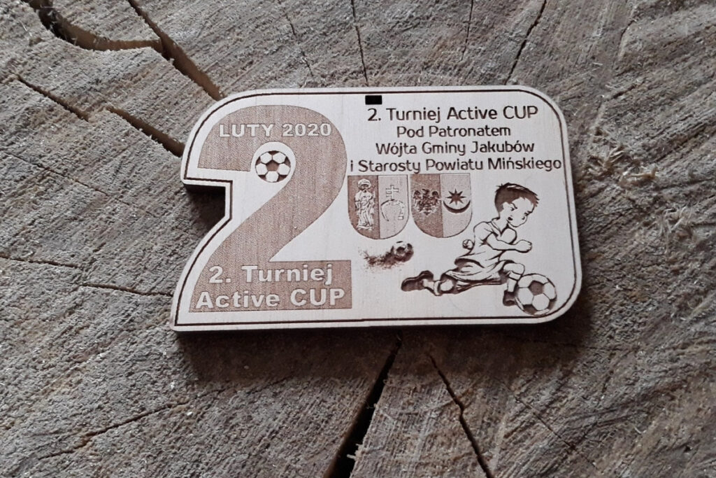 Drewniany medal dla młodych piłkarzy na turniej Active Cup, z grawerem dużej 2, młodym piłkarzem, logotypami, wykonany z jasnej płyty drzewnej bez osmaleń.