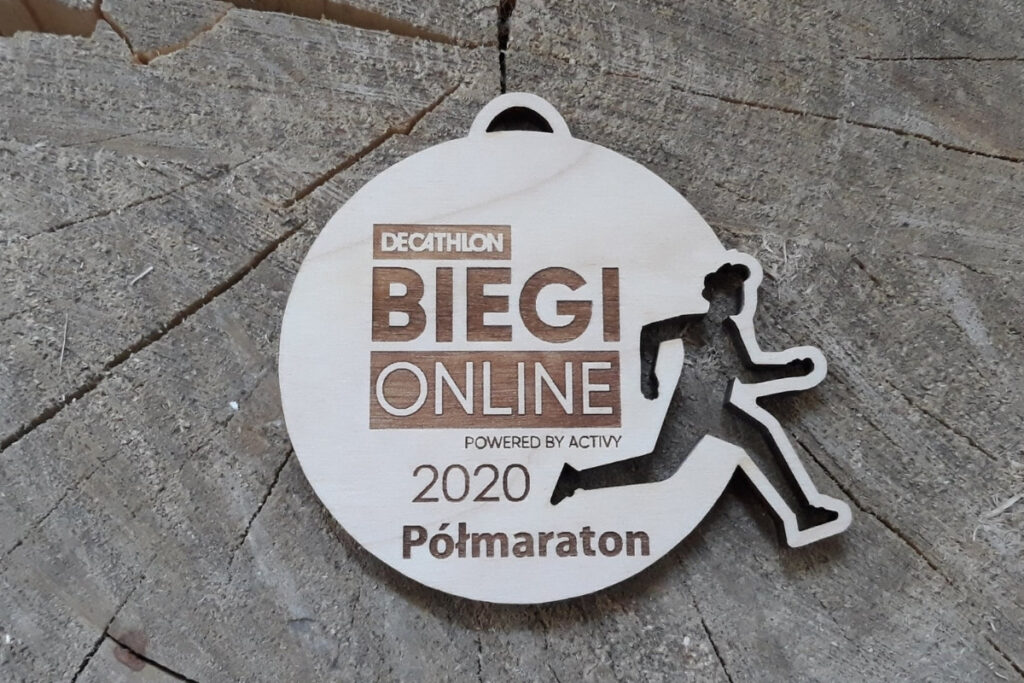 Okrągły drewniany medal ażurowy z precyzyjnie wyciętą sylwetką biegacza w ruchu, personalizowany grawer na biegi wirtualne on-line, wykonany z jasnej brzozy bez przypaleń.