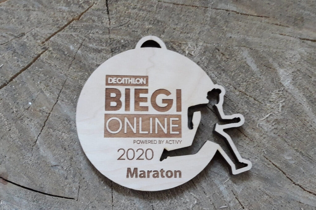 Okrągły drewniany medal ażurowy z precyzyjnie wyciętą sylwetką biegacza w ruchu, personalizowany grawer na biegi wirtualne on-line, wykonany z jasnej brzozy bez przypaleń.