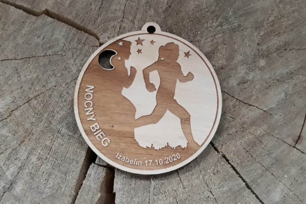Okrągły drewniany medal na bieg nocny, z precyzyjnym grawerem gwiazd oraz sylwetek biegaczy na tle nocnego nieba, wykonany z czystej płyty brzozowej bez śladów przypaleń czy zabrudzeń.