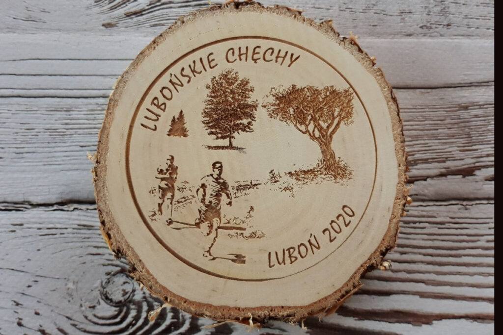 Drewniany medal na „Lubońskie Chechy” wykonany na naturalnym plastrze brzozy z korą, z grawerem logotypu wydarzenia, daty oraz biegacza, czysta powierzchnia bez osmaleń.
