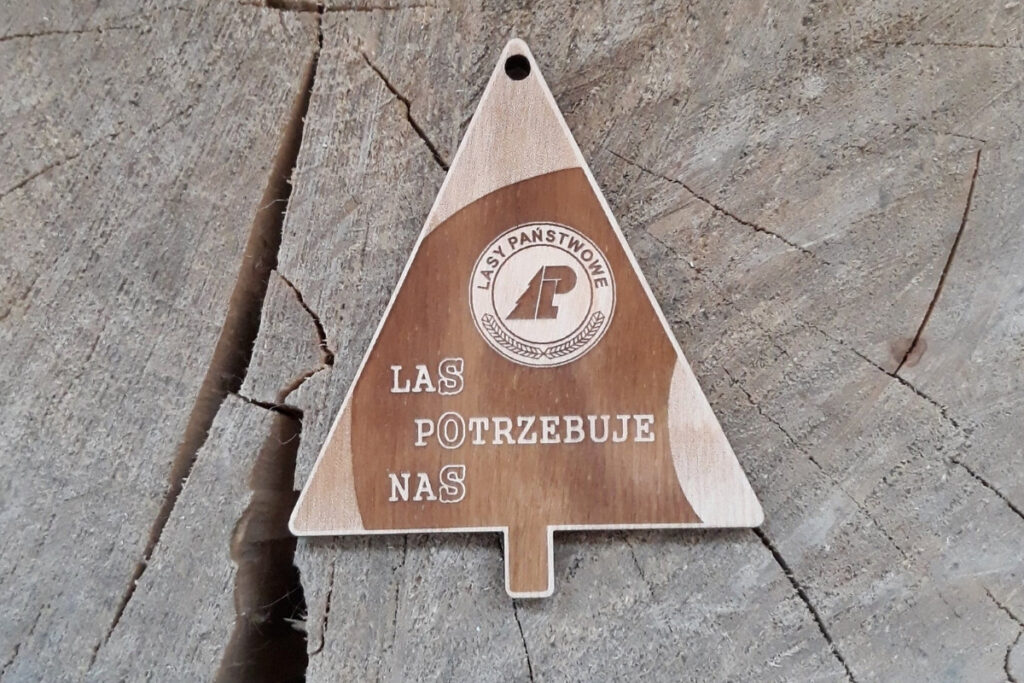 Trójkątny drewniany medal "SOS - Las potrzebuje nas", wykonany z czystej brzozy bez osmaleń, zawieszony na ekologicznym sznurku.