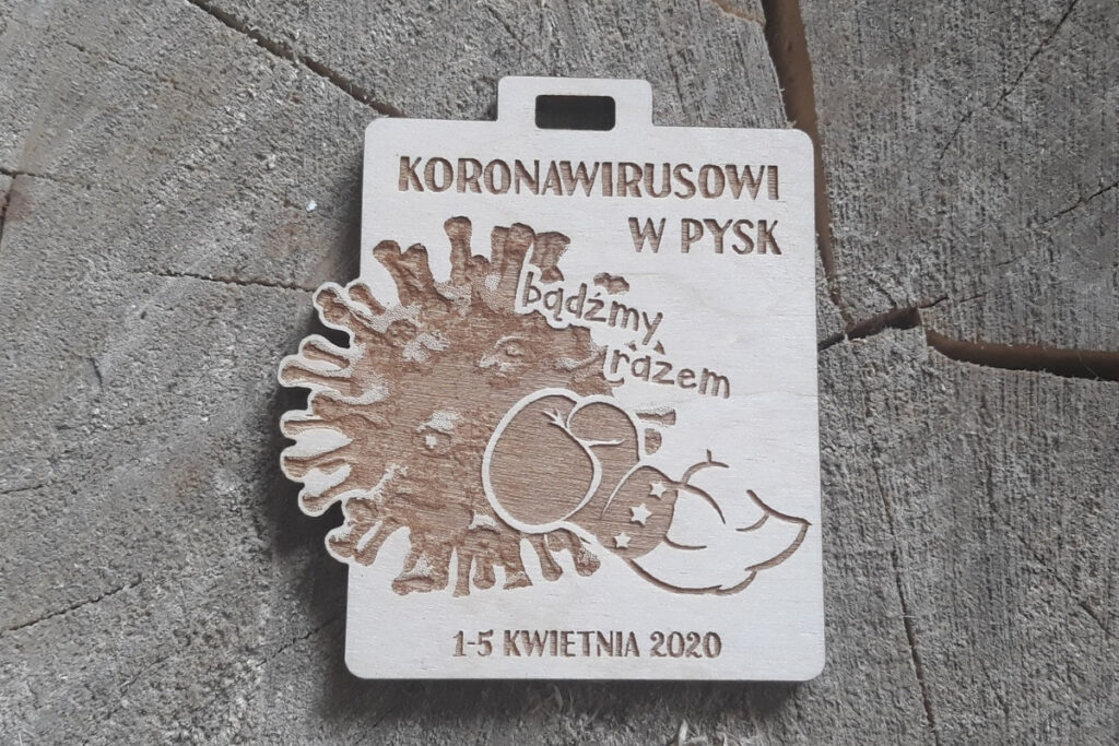 Prostokątny drewniany medal z grawerem cząsteczki wirusa z napisem „Koronawirusowi w pysk!”, upamiętniający sportową wytrwałość w dobie pandemii, wykonany z czystej brzozy bez śladów osmaleń.