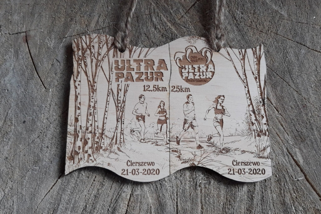 Zestaw dwóch drewnianych medali modułowych na bieg Ultra Pazur, które po złożeniu tworzą spójną grafikę.