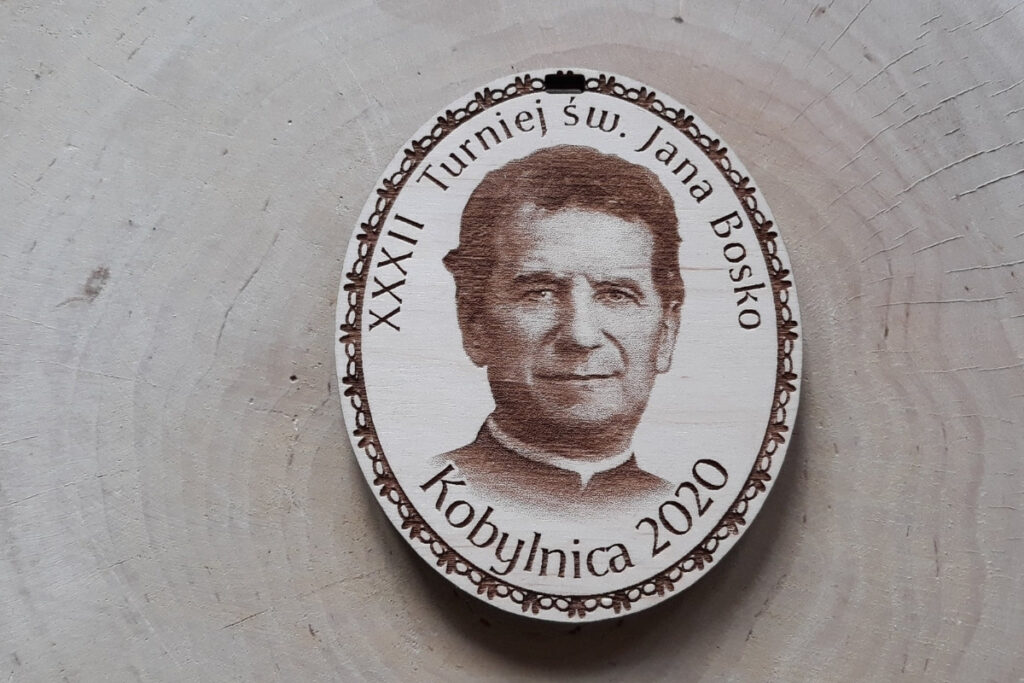 Owalny drewniany medal na „Turniej św. Jana Bosko”, z precyzyjnie wygrawerowanym wizerunkiem świętego, oraz napisem okolicznościowym, wykonany z czystej płyty brzozy bez śladów dymu i osmaleń.
