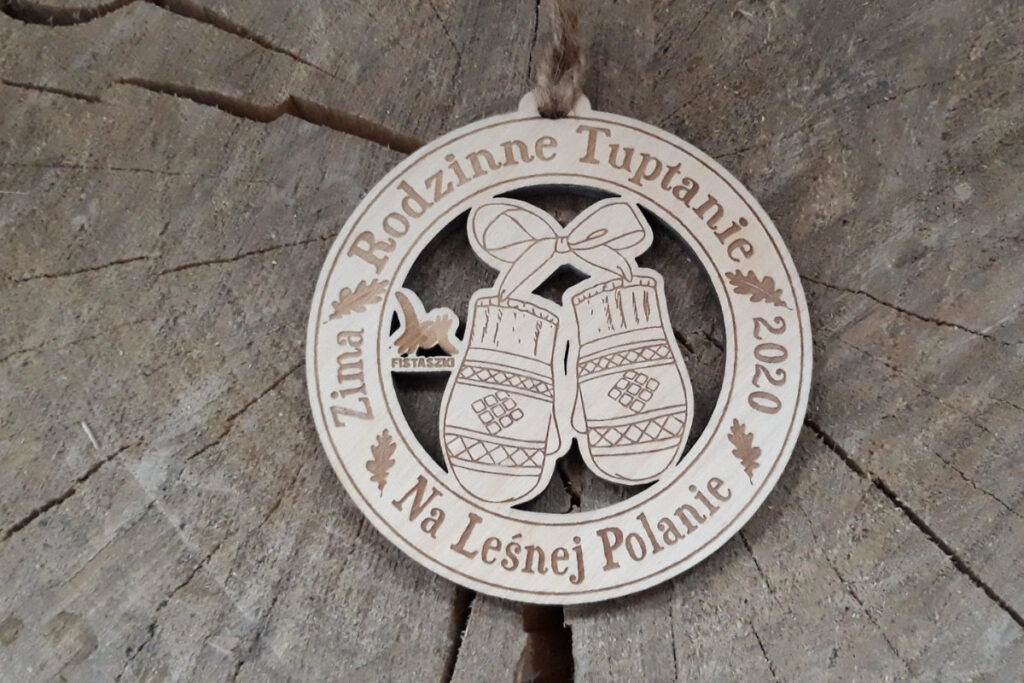 Ażurowy drewniany medal na Rodzinne Tuptanie z precyzyjnie wyciętym motywem zimowych rękawiczek.