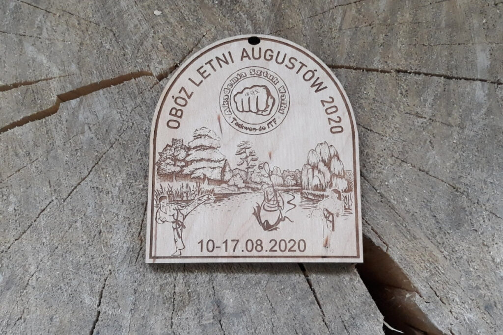 Obóz letni w Augustowie. Drewniane medale z kajakiem dla młodych uczestników
